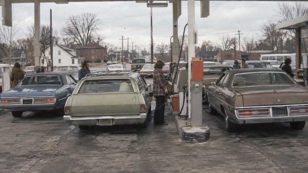 American gas station with 1970s cars waiting at the pumps